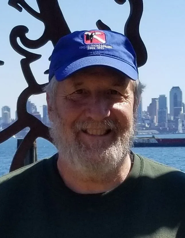 Homme souriant portant une casquette bleue avec un logo de plongée