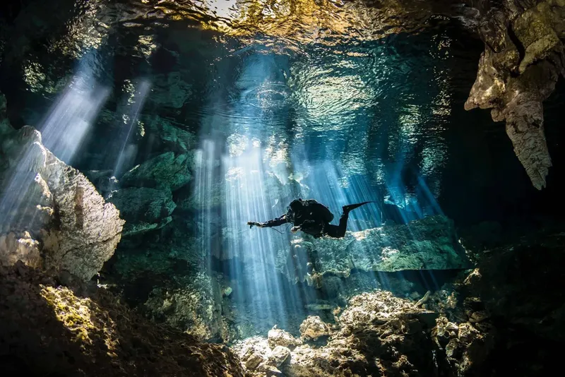 Plongeur explorant une grotte sous-marine éclairée par des rayons de soleil