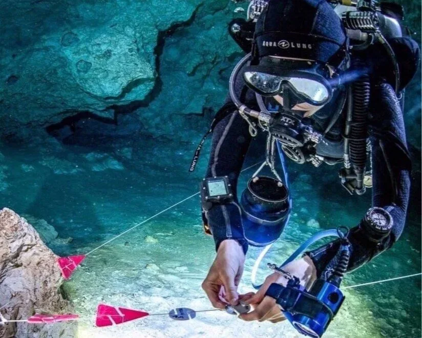 Plongeur manipulant un appareil de mesure sous l'eau en grotte