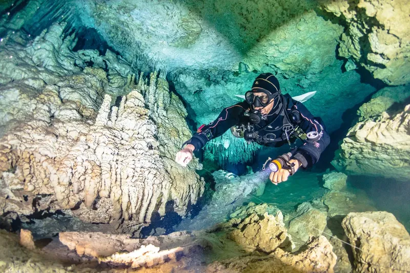 Plongeur explore une grotte sous-marine éclairée par une lampe torche