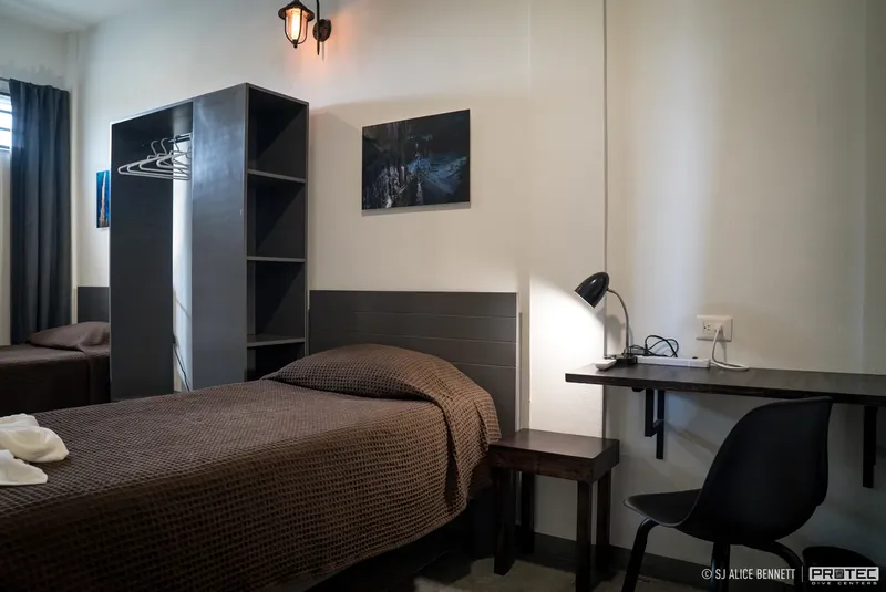 Chambre simple avec lit, bureau, lampe et espace de rangement sombre