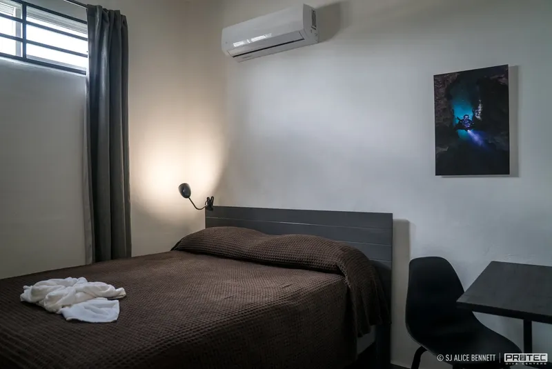 Chambre d'hôtel simple avec un lit, une climatisation et une décoration murale