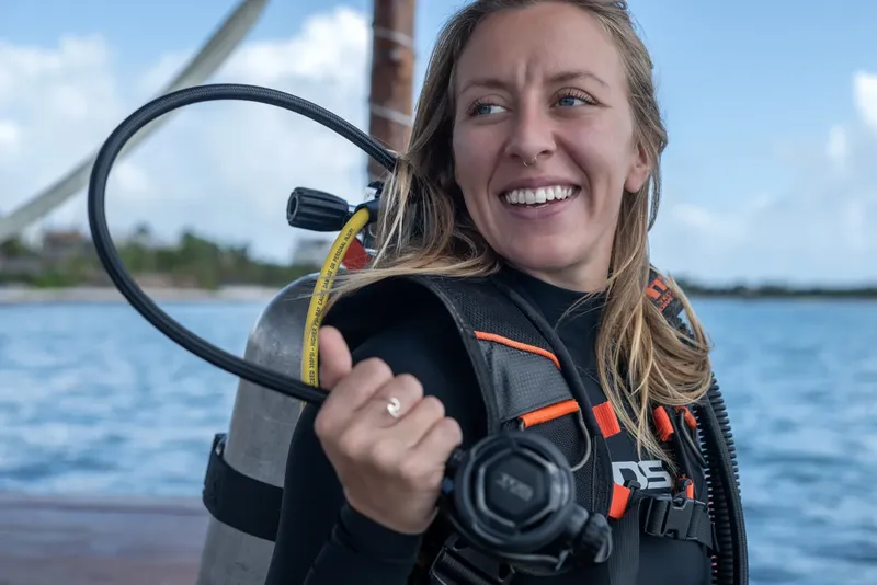 Plongeuse souriante avec son équipement sur un ponton ensoleillé
