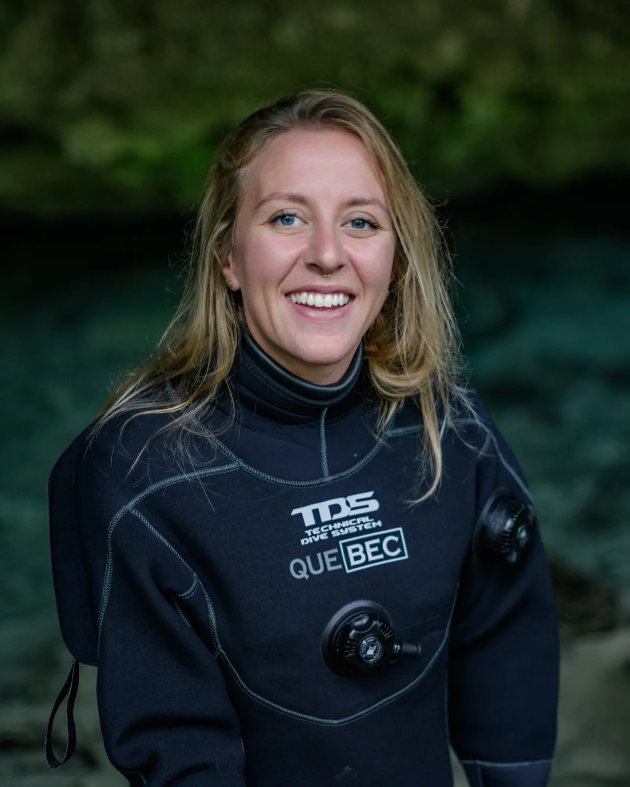 Femme souriante portant une combinaison de plongée noire avec logo