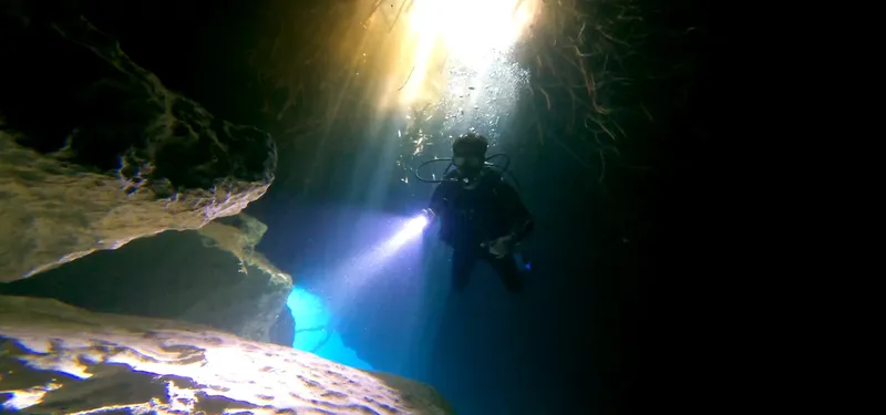 Plongeur explorant une grotte sous-marine éclairée par un faisceau lumineux