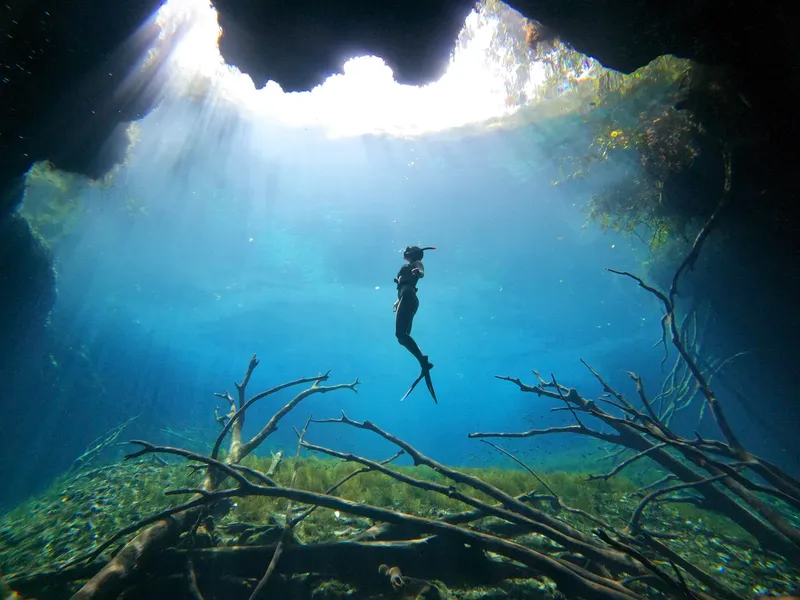 Apnea en exploration d'une grotte sous-marine éclairée par le soleil
