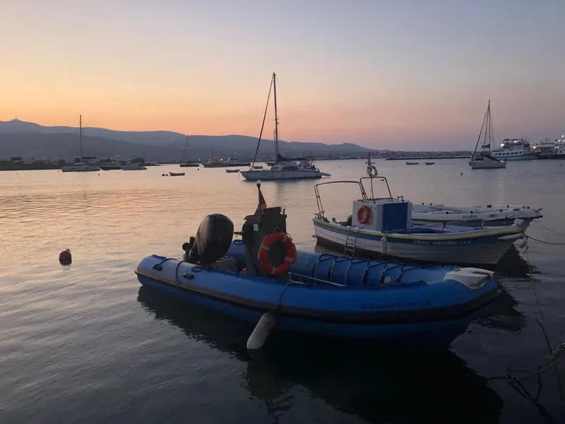 Plusieurs bateaux amarrés dans un port au coucher du soleil calme