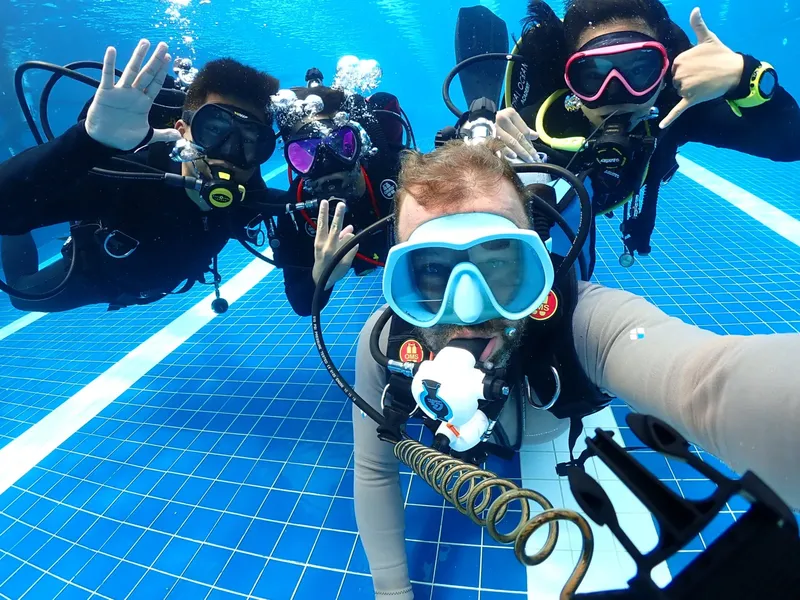 Plongeurs souriants prennent un selfie sous l'eau dans une piscine carree