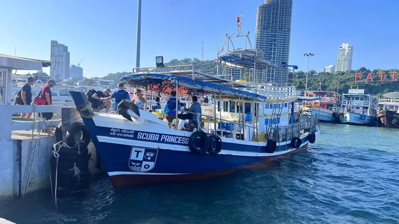 Bateau de plongée amarré à un quai avec des personnes à bord