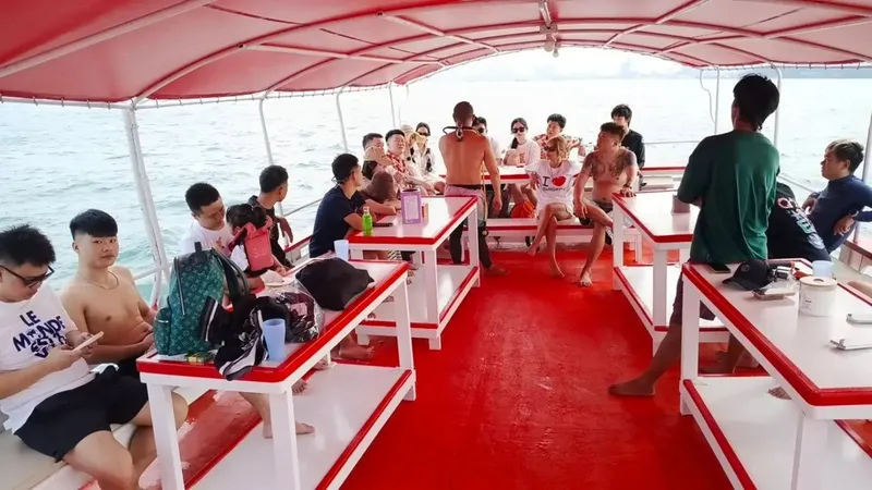 Groupe de personnes sur un bateau rouge en direction d'un site de plongée