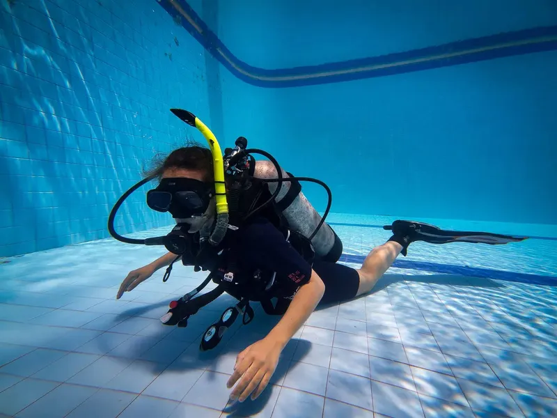 Plongeuse en formation nageant sous l'eau dans une piscine carrelée