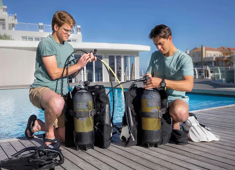 Deux plongeurs vérifient leur équipement près d'une piscine ensoleillée