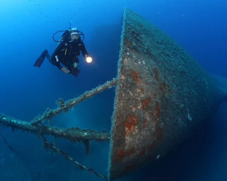 Plongeur explorant l'épave d'un grand navire sous l'eau bleue