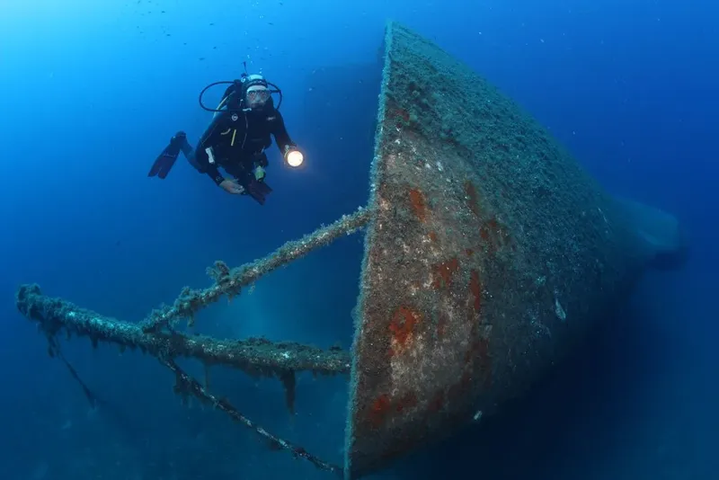 Plongeur explorant l'épave d'un grand navire sous l'eau bleue