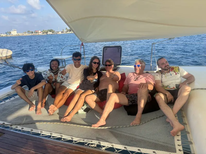 Groupe de personnes souriantes se relaxent sur le filet d'un bateau