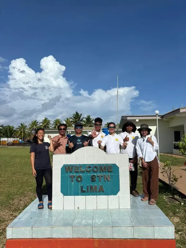 Groupe de personnes souriantes devant une structure avec l'inscription Lima