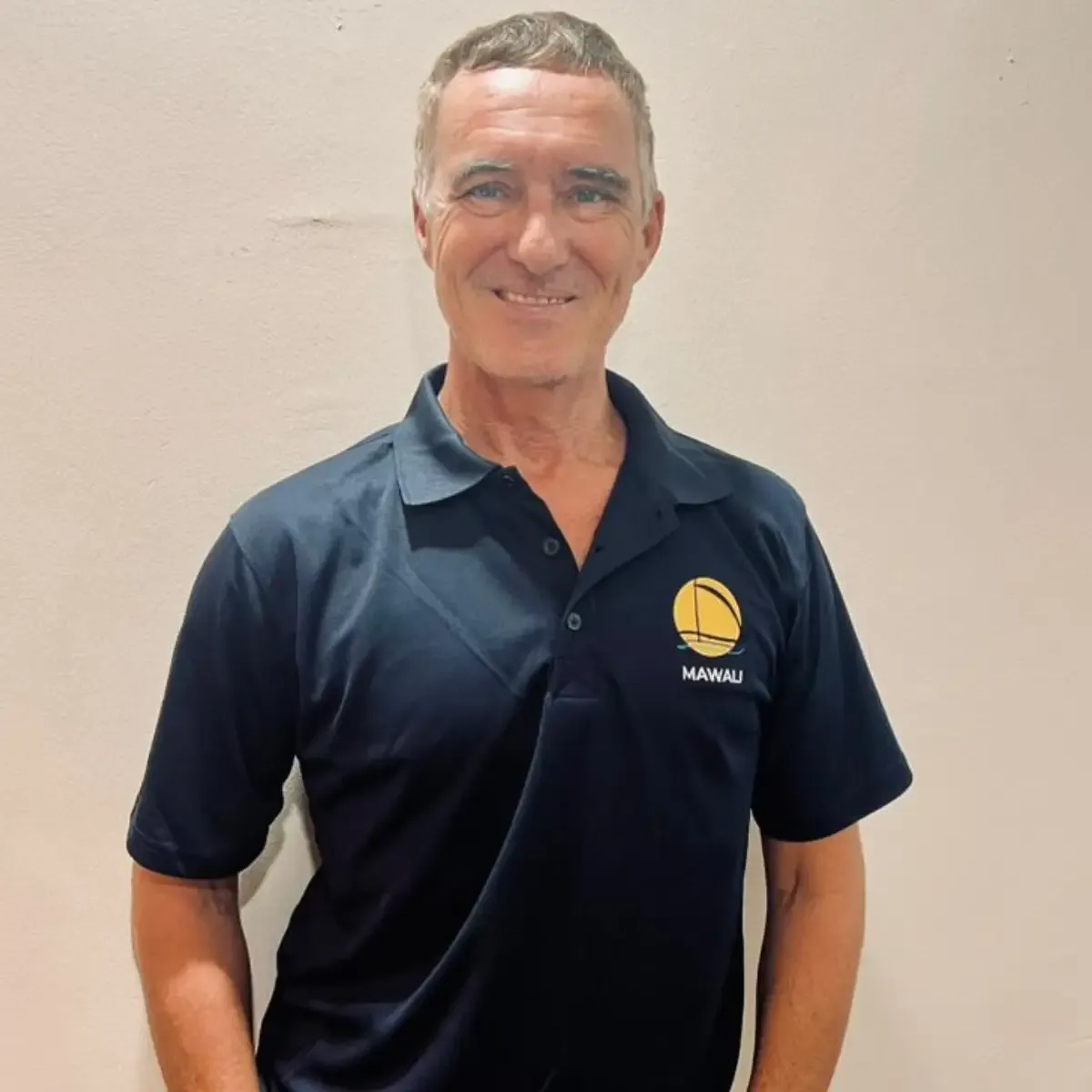 Homme souriant portant un polo bleu avec un logo jaune