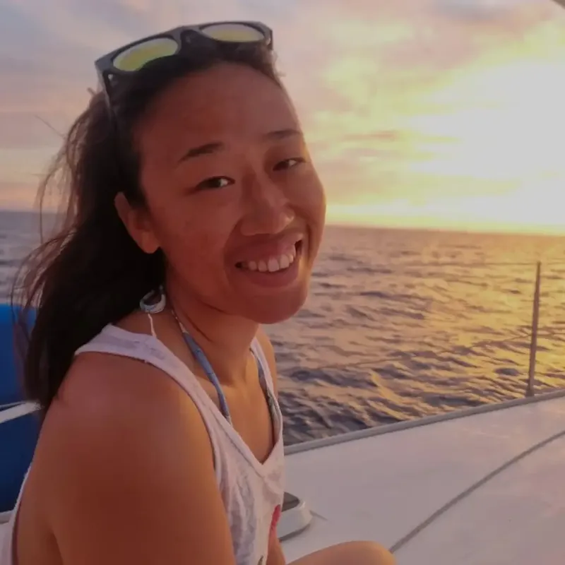 Jeune femme souriante sur un bateau en mer au coucher du soleil