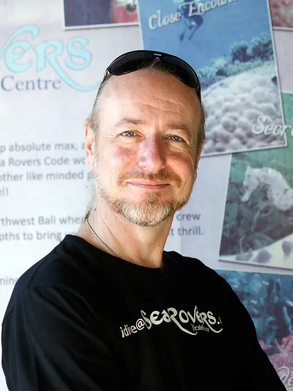 Homme souriant devant une affiche de centre de plongée marine