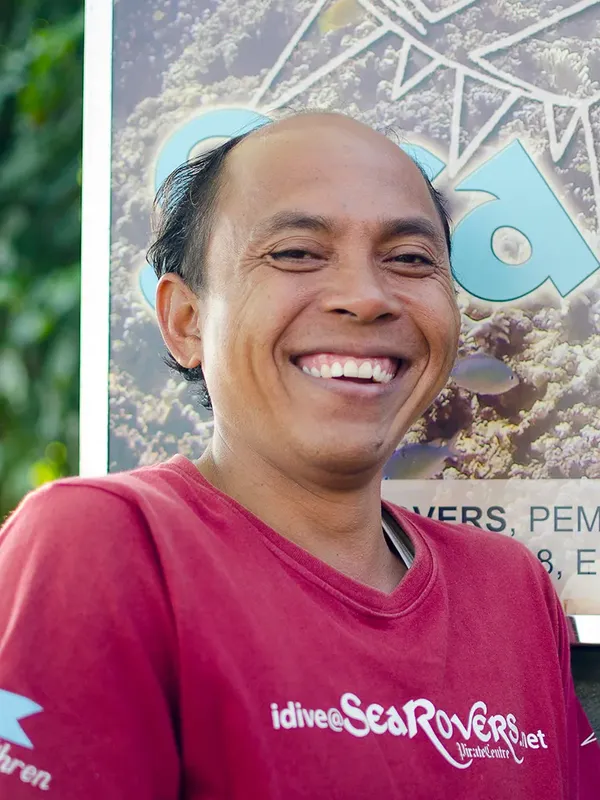Portrait souriant d'un homme portant un t-shirt rouge devant un décor marin