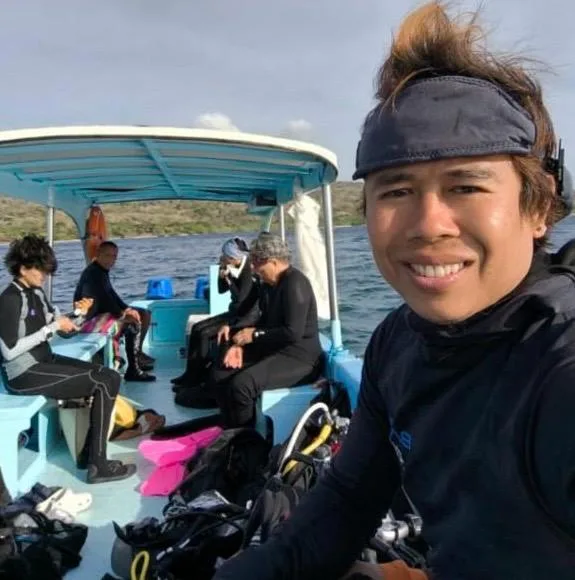 Plongeurs souriants sur un bateau, équipement de plongée visible autour