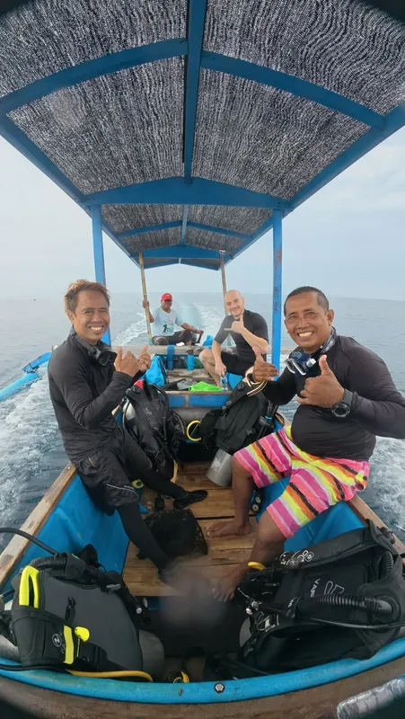 Quatre personnes souriantes à bord d'un bateau de plongée en mer