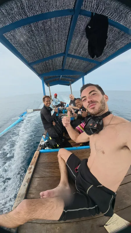 Groupe de plongeurs souriants sur un bateau en direction du site