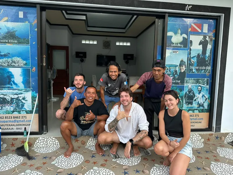 Groupe de personnes souriantes devant l'entrée d'un centre de plongée