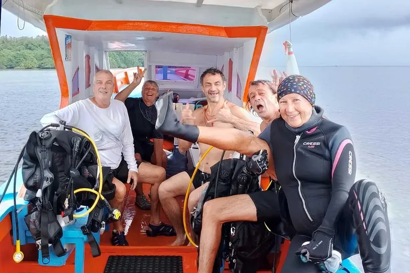 Groupe de plongeurs souriants à bord d'un bateau orange et bleu