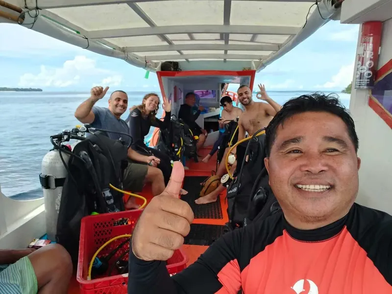 Groupe de plongeurs souriants sur un bateau en mer, pouce levé