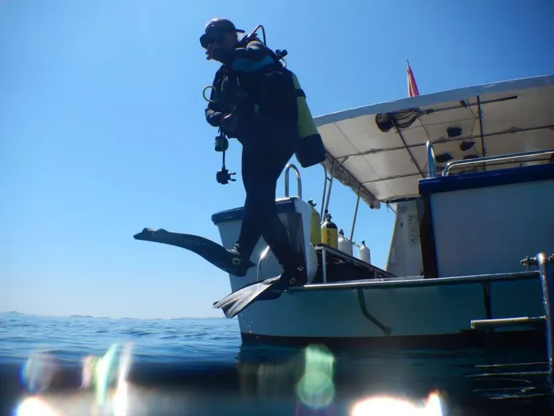 Plongeur s'apprête à sauter d'un bateau en mer, équipé
