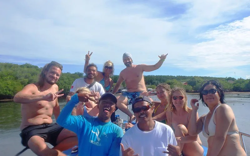 Groupe de personnes souriantes sur un bateau en mer, signe de la paix