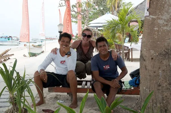 Trois personnes souriantes assises sur un banc en bois sur une plage