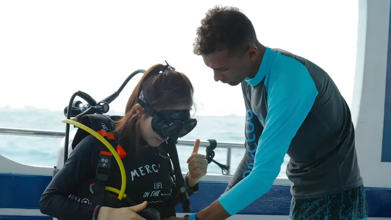 Deux plongeurs sur le bateau, un instructeur aide à préparer l'équipement
