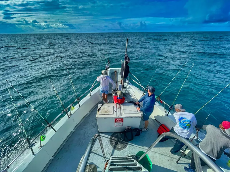 Personnes à bord d'un bateau de pêche en mer, ciel bleu