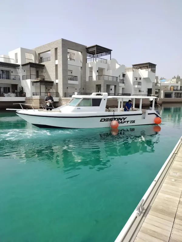 Bateau de plongée amarré dans un port avec des bâtiments blancs