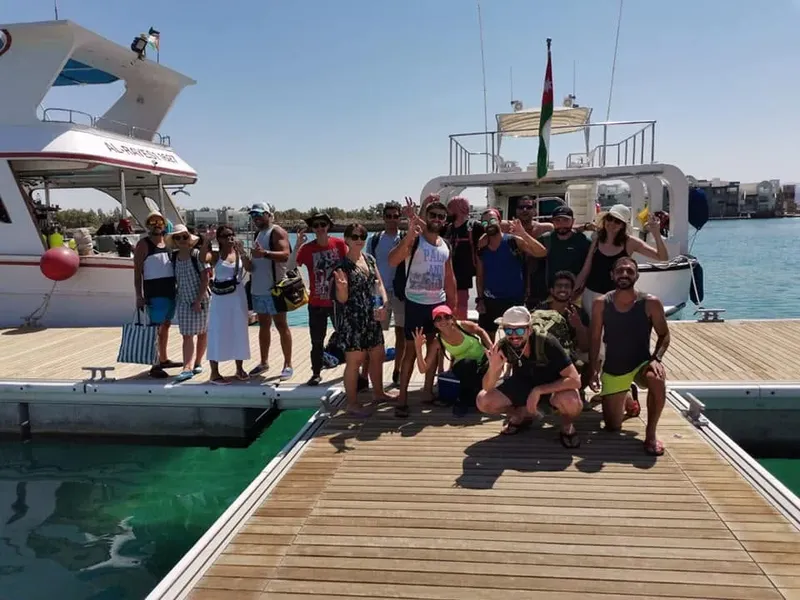 Groupe de personnes souriantes posant sur un ponton devant un bateau