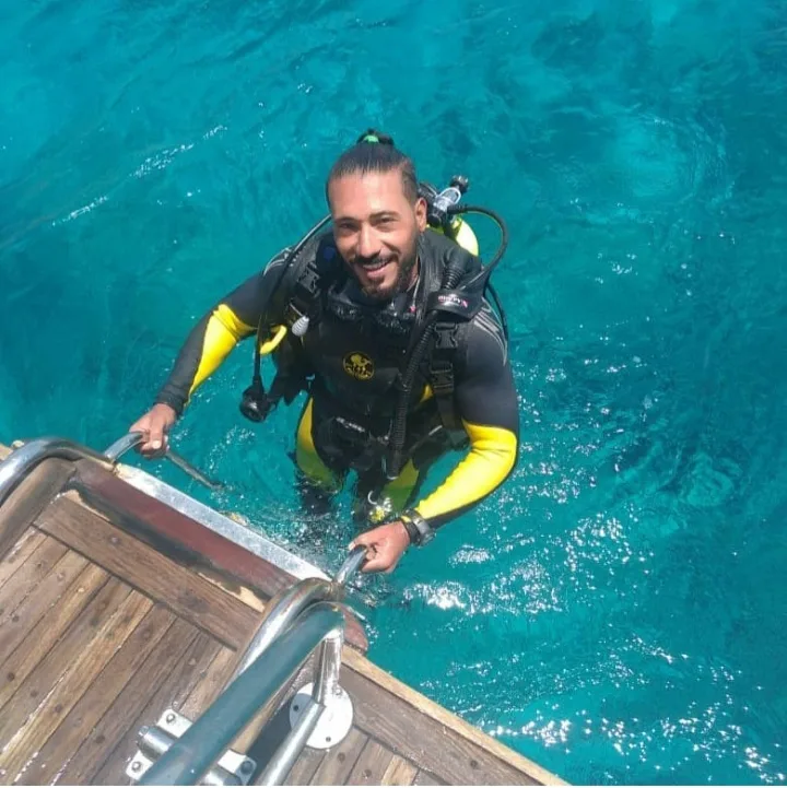 Plongeur souriant sortant d'un bateau sur une eau turquoise claire