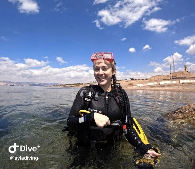 Plongeuse souriante avec équipement complet dans une eau claire et ensoleillée