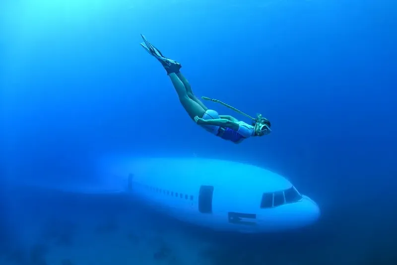 Apnée au-dessus d'un avion coulé, plongeuse en pleine exploration sous-marine