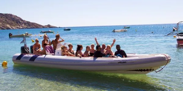 Groupe de personnes souriantes à bord d'un bateau semi-rigide en mer