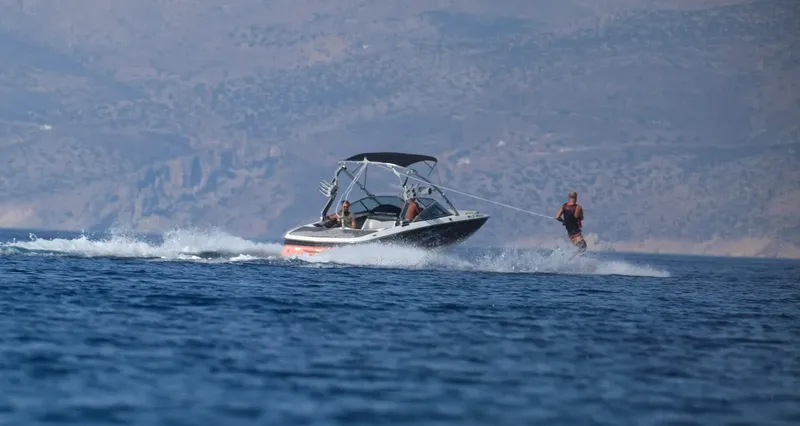 Personnes pratiquant le ski nautique tirées par un bateau rapide en mer
