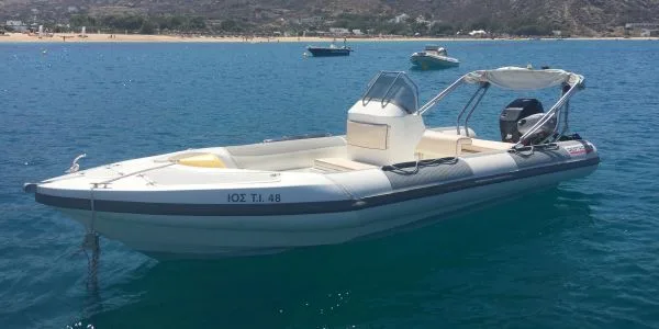 Bateau semi-rigide blanc et bleu amarré dans une mer turquoise calme