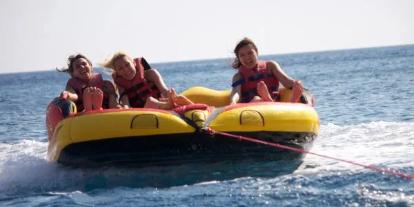 Trois personnes souriantes sur un bouée tractée en mer