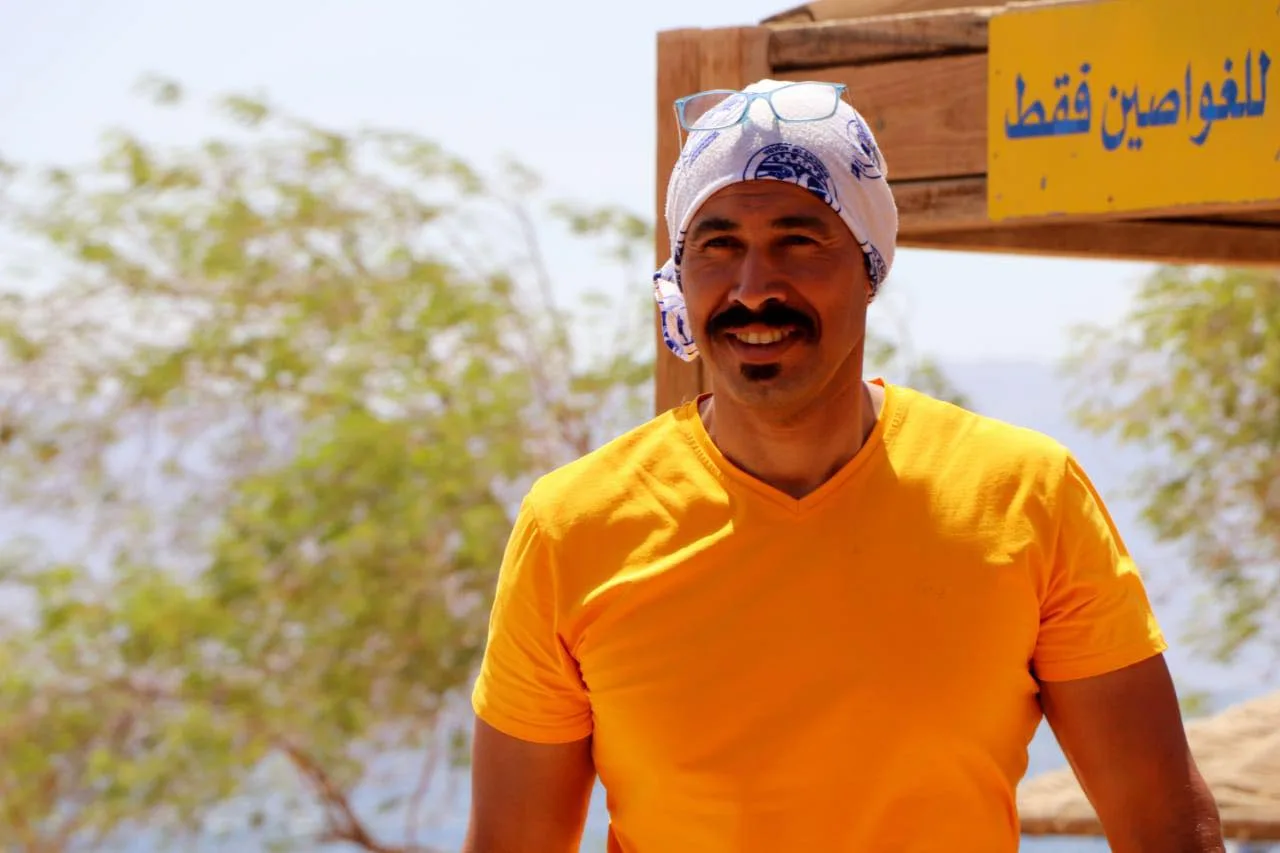 Homme souriant portant un bandeau et un t-shirt jaune en extérieur