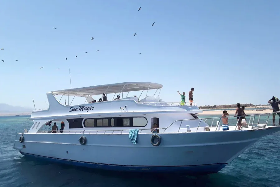 Bateau de plongée blanc avec des passagers et un ciel bleu clair