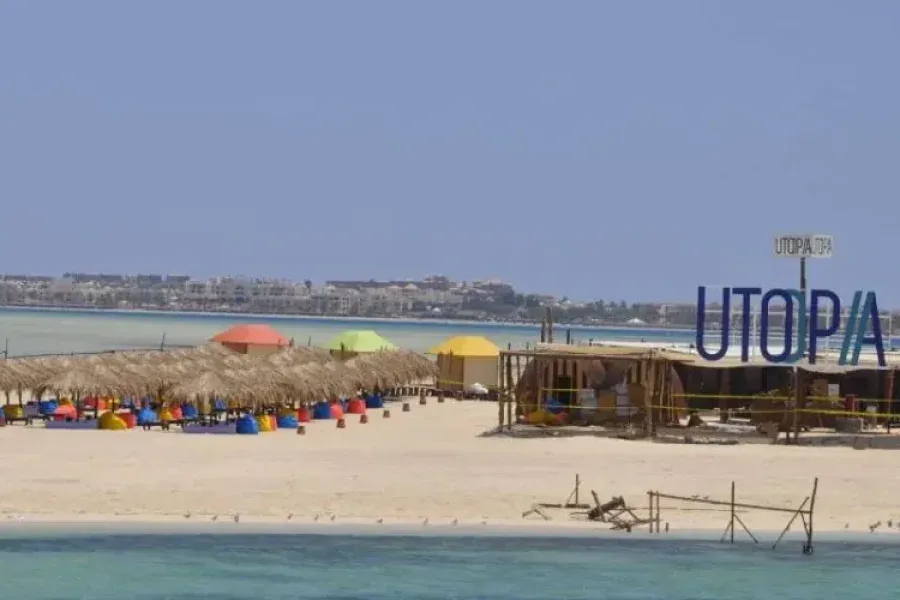 Plage avec parasols, bâtiments et le nom Utopia en grand