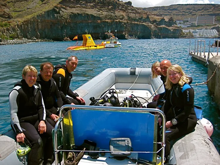 Groupe de plongeurs souriants à bord d'un bateau semi-rigide bleu
