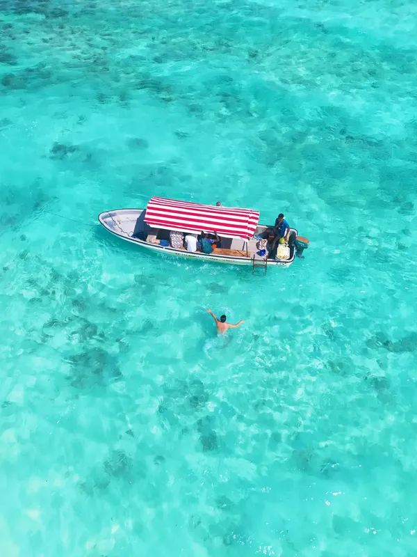 Vue aérienne d'un bateau et d'une personne dans une eau turquoise