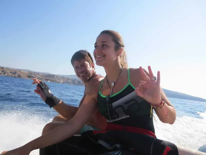 Deux personnes souriantes sur un bateau en mer, signe de paix